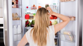 Rear,View,Of,Young,Woman,Looking,In,Fridge,At,Kitchen