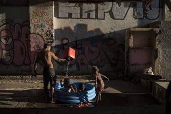 Homem banha crianças em uma favela do Rio de Janeiro