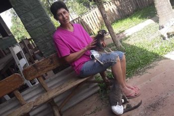 A cuidadora Carla com a paraplégica Bebel no colo. No chão, Branco, o gato com fraldas e bandagens